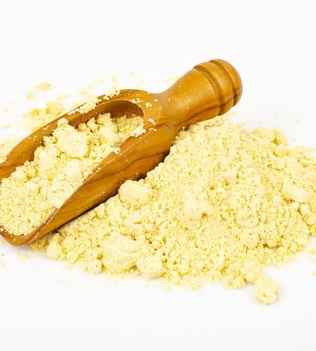 Pile of corn flour with scoop on white background. Studio Photo